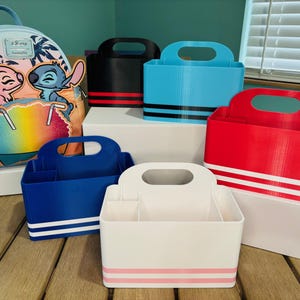 May include: A collection of colorful storage caddies and a backpack. The caddies are in various colors, including blue, red, black, and white, with horizontal stripes. The backpack features a colorful design with cartoon characters and a tropical theme.