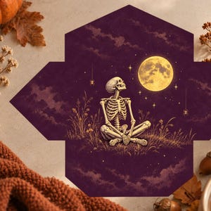 May include: A hexagonal envelope featuring a dark purple background with a skeleton sitting in a cross-legged position on a grassy hill. The scene includes a large yellow full moon, scattered stars, and two small spiders hanging from threads.