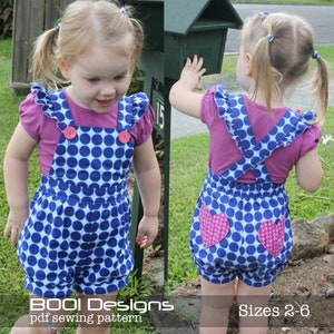 May include: A blue and white polka dot overall dress with pink heart accents. The dress has a pink ruffled top and is worn by two young girls. The dress is available in sizes 2-6.  BOO! Designs pdf sewing pattern.