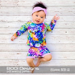 Könnte beinhalten: Ein Baby trägt ein langärmliges Oberteil mit Blumenmuster und eine passende Shorts mit einem rosa-weiß gestreiften Stirnband. Das Outfit ist in den Größen NB-2 erhältlich. "BOO! Designs pdf sewing pattern" steht unten im Bild.