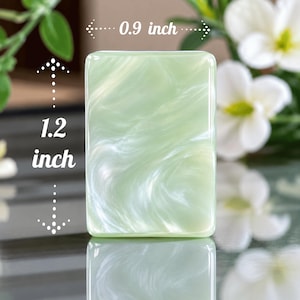 May include: A rectangular light green and white marbled piece with a smooth, glossy finish. The object measures 0.9 inches in width and 1.2 inches in height, as indicated by the white arrows and text printed directly on the image.