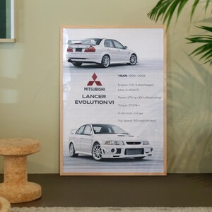 Könnte beinhalten: Gerahmter Druck mit einem weißen Mitsubishi Lancer Evolution VI. Der Druck enthält Fahrzeugspezifikationen wie Motortyp, Leistung, Drehmoment und Höchstgeschwindigkeit von 249 km/h. Baujahr des Autos: 1999-2001. Das Bild ist in einem Holzrahmen.