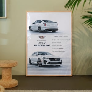 May include: A framed print showcasing a white Cadillac CT5-V Blackwing. The print displays front and rear views of the car and specifications: Engine 6.2L Supercharged V8, Power: 668 hp, Torque: 893 Nm, 0-60 mph 3.4 sec, and Top Speed 322 km/h.