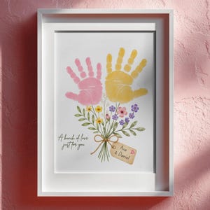 May include: A framed print featuring a pink handprint and a yellow handprint arranged to resemble a flower bouquet with green stems and small colourful flowers. The text reads A bunch of love just for you and a tag labelled Ava & Daniel.