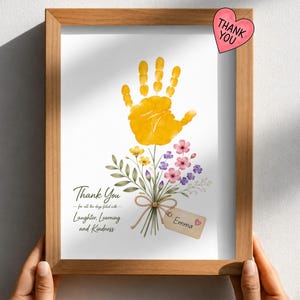May include: A framed print featuring a yellow handprint as a flower bloom atop a bouquet of watercolor flowers. The text reads: Thank You for all the days filled with Laughter, Learning and Kindness. A tag attached to the stems says Emma.