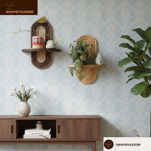 May include: Two wooden wall shelves with a woven cane design, each holding a potted plant. The shelves are mounted on a light blue patterned wall. The text "SHOPBYAZEEM" is visible in the image.