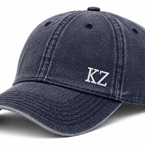 May include: A navy blue baseball cap with a curved brim. The cap features the white letters "KZ" embroidered on the front. The hat has a distressed, vintage look.