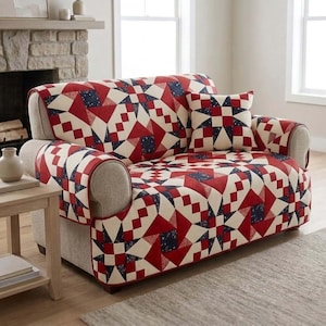 May include: A sofa cover and cushion set with a geometric pattern in red, white, and navy blue. The sofa has a light beige frame. The set is designed to protect and enhance the look of a sofa.
