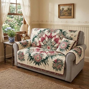 May include: A grey sofa with a floral quilt cover and matching cushion. The quilt has a cream background with red and green floral patterns. The sofa is in a room with a window and a small table.