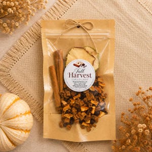 May include: A clear plastic and brown paper pouch containing a Fall Harvest simmer pot blend with dried apple slices, cinnamon sticks, and orange peel. A round white label features the text Fall Harvest and instructions for use.