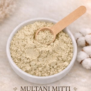 May include: A white ceramic bowl filled with Multani Mitti (Fuller's Earth) powder, with a wooden scoop resting inside. The powder is a light beige color. Text at the bottom reads: Natural, Purifying, Brightening.