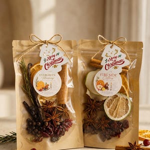 May include: Two clear stand-up pouches filled with dried holiday potpourri ingredients. The left bag labelled Evergreen Morning contains rosemary, orange slices, cinnamon sticks, star anise, and cranberries. The right bag labelled Fireside Citrus features dried pear, orange, grapefruit, cinnamon, star anise, and cranberries, each topped with a Merry Christmas tag.