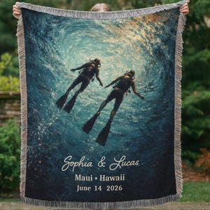May include: Woven throw blanket featuring an underwater scene with two scuba divers. The blanket has a dark blue background with a light blue and yellow gradient. Text on the blanket reads "Sophia & Lucas, Maui &bull; Hawaii, June 14 2026."