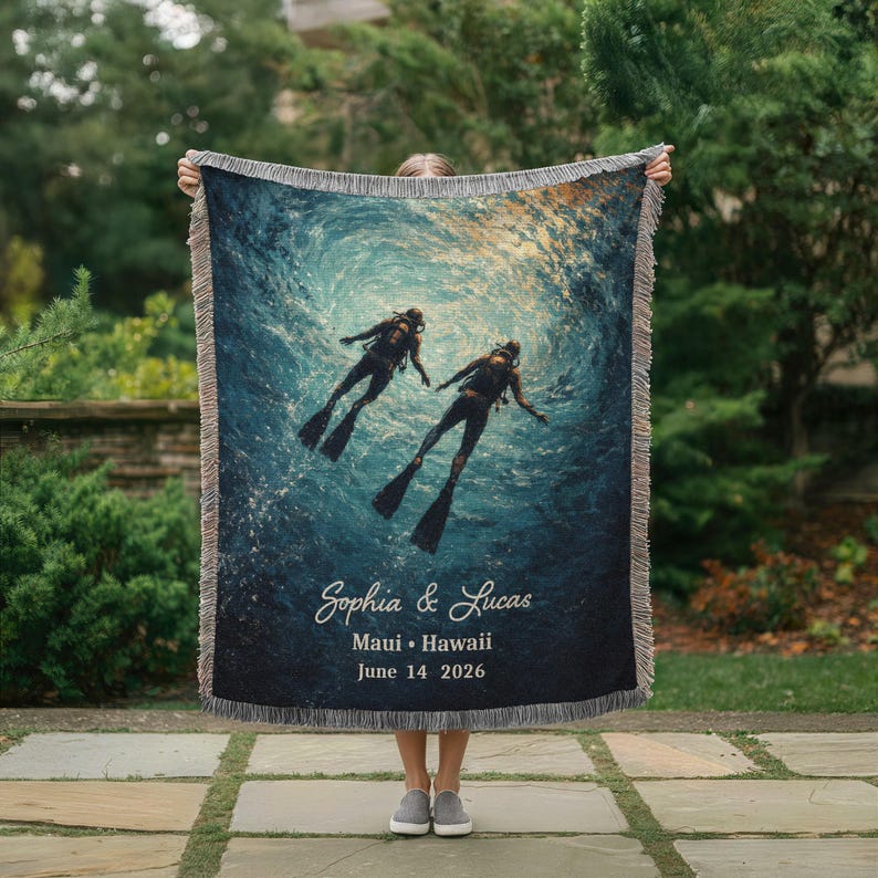 May include: Woven throw blanket featuring an underwater scene with two scuba divers. The blanket has a dark blue background with a light blue and yellow gradient. Text on the blanket reads "Sophia & Lucas, Maui &bull; Hawaii, June 14 2026."