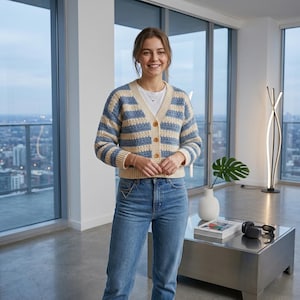 Könnte beinhalten: Ein blau-cremefarbener Cardigan mit Holzknöpfen und Streifen. Der V-Ausschnitt-Pullover wird mit einer blauen Jeans kombiniert. Der Cardigan ist ein gemütliches, lässiges Kleidungsstück, perfekt zum Überziehen. Das Outfit ist für den Alltag geeignet.