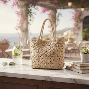 Puede incluir: Bolso tote beige tejido a mano con un patrón floral. El bolso tiene dos asas y está sobre una encimera de mármol. Gafas de sol, una jarra de vidrio con agua, limón y menta, y una pequeña suculenta también están en la encimera.