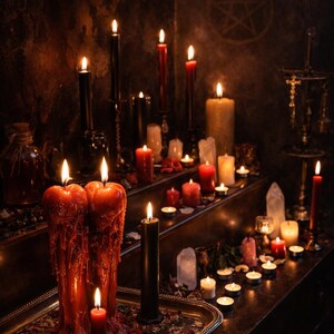 May include: A collection of numerous lit candles in various sizes and colours, including deep red and black, arranged on tiered surfaces. Two large, thick red candles with heavy wax drips sit on a silver tray alongside a thin red candle.