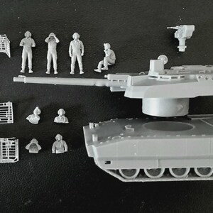 Op de afbeelding: Een grijze plastic modeltankset bestaande uit een hoofdromp, een koepel met een lange loop en een apart machinegeweeronderdeel. De set bevat diverse kleine grijze plastic figuren van bemanningsleden in verschillende houdingen en rasterpanelen.