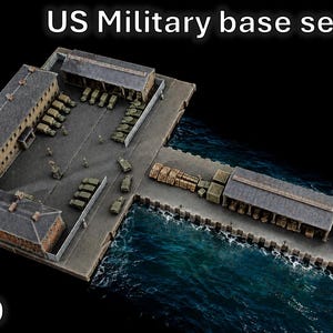 Pode incluir: Uma maquete em escala 1/700 de uma seção de base militar dos EUA com vários edifícios, um píer que se estende até a água e veículos em miniatura. A cena inclui estruturas cinzas, um pátio pavimentado e caixas de carga.