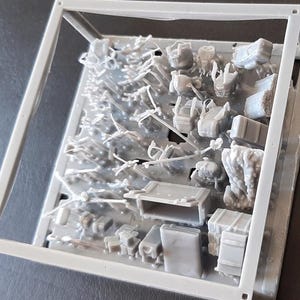 Puede incluir: Un kit de modelo de pl&aacute;stico gris con varios componentes en miniatura, incluyendo cajas, mochilas y otros elementos de tem&aacute;tica militar, se muestra dentro de un marco de pl&aacute;stico transparente. La imagen muestra dos kits id&eacute;nticos.