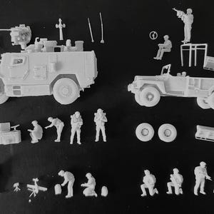 Op de afbeelding: Een verzameling onbeschilderde lichtgrijze plastic modelbouwonderdelen, waaronder een gepantserd voertuig, een open vrachtwagen, diverse soldatenfiguren in verschillende houdingen, reservewielen, antennes en uitrustingsaccessoires voor montage.