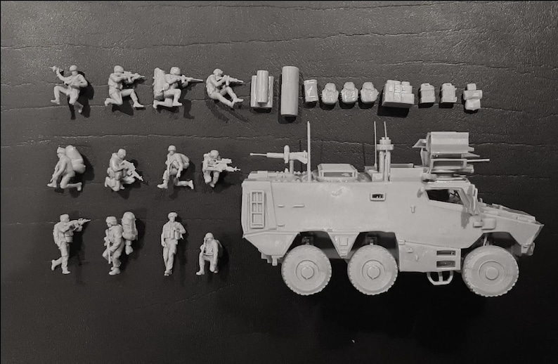 May include: A collection of unpainted miniature military figures and a light gray armored vehicle. The figures are in various action poses, including kneeling and aiming rifles. Additional accessories are also included.