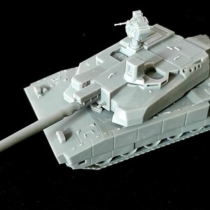 Pode incluir: Um modelo em escala de um tanque de batalha principal em pl&aacute;stico cinza, apresentando um canh&atilde;o longo, uma torre girat&oacute;ria e uma esta&ccedil;&atilde;o de metralhadora montada no topo. O corpo do tanque exibe blindagem detalhada, saias laterais e esteiras.