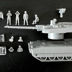 Pode incluir: Um kit de modelo de tanque em pl&aacute;stico cinzento com um casco principal, uma torre com um canh&atilde;o longo e uma metralhadora separada. O conjunto inclui v&aacute;rias pequenas figuras de soldados por pintar e pain&eacute;is de grelha retangulares.
