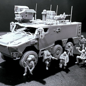 May include: A gray model of a military armored vehicle with multiple antennas and a mounted weapon system. Miniature soldiers are positioned around the vehicle, some holding rifles. The model is detailed and appears to be a scale replica.