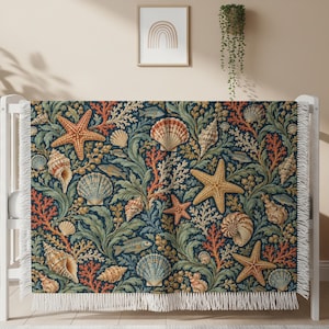 May include: A rectangular throw blanket featuring a dense, intricate pattern of orange starfish, various seashells, and green seaweed set against a dark navy blue background. The blanket has a white fringed edge along the top and bottom sides.