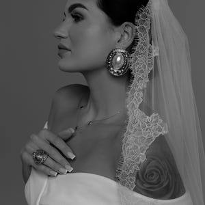 Bride wearing ivory wedding veil gathered at comb with Chantilly lace edge and long flowing train