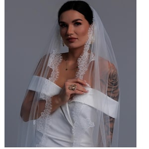 Bride wearing ivory wedding veil gathered at comb with Chantilly lace edge and long flowing train