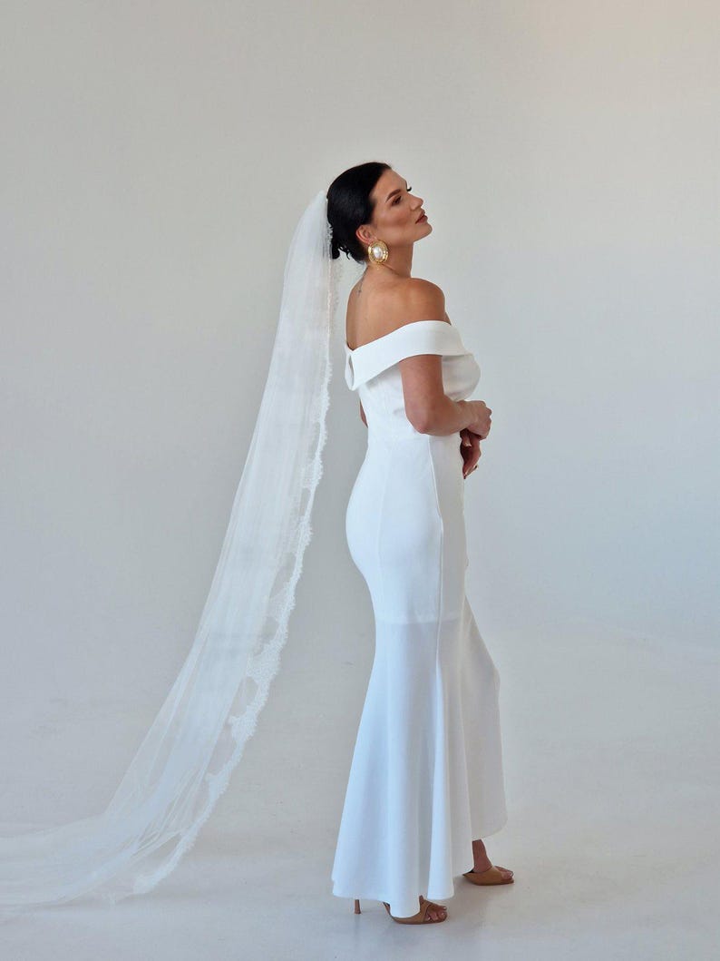 Bride wearing ivory wedding veil gathered at comb with Chantilly lace edge and long flowing train