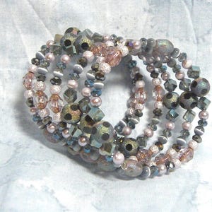 May include: A multi-strand bracelet made of various beads, including iridescent glass beads, pink and brown beads, and black and white polka dot beads.
