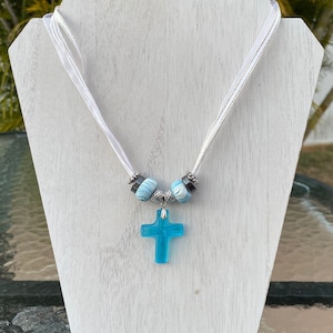 Necklace: White Ribbon Corded Choker with a Large Blue Cross and Silver, Onyx Colored, and Blue/Cream Beads