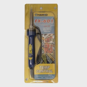 Puede incluir: Un soldador con control de temperatura Hakko FX-601 en un embalaje de plástico amarillo y transparente. El soldador es azul y plateado con un cable negro. El texto en el paquete incluye "FX-601", "Temp Control" y "251-540°C".