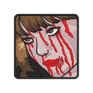 Puede incluir: Parche bordado con un rostro estilizado con cabello castaño y vetas rojas. El rostro tiene ojos detallados, una nariz definida y labios rojos. El parche tiene un borde negro y un fondo texturizado.