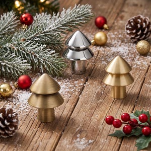 May include: Three metal cabinet knobs shaped like stylized Christmas trees. One knob has a polished silver finish, while the other two feature a brushed gold finish. Each knob consists of a cylindrical base topped with two stacked conical tiers.