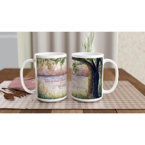 Puede incluir: Dos tazas de cerámica blanca con una ilustración en acuarela de un paisaje con un gran árbol junto a un cuerpo de agua. El texto en las tazas dice "like a tree planted by streams of water" y "Psalm 1:3". Las tazas tienen un asa curva.