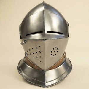 May include: A silver-colored medieval helmet with a pointed top and a hinged visor. The visor features small circular ventilation holes and horizontal eye slits. A leather strap secures the helmet around the neck.