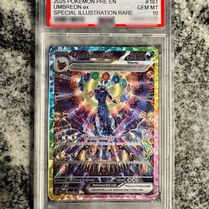 May include: A graded Umbreon ex trading card in a clear plastic slab. The card features a colorful, intricate illustration of the Umbreon character with a holographic finish. The label at the top reads 2025 POKEMON PRE EN UMBREON ex #161 GEM MT 10.