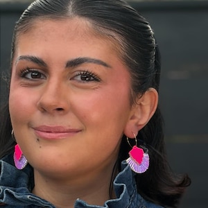 Peut inclure: Deux femmes portant des chemises en jean et des boucles d'oreilles colorées. L'une porte des boucles d'oreilles roses et violettes en forme d'éventail, l'autre des boucles d'oreilles carrées roses et violettes. Les boucles d'oreilles sont le point central.