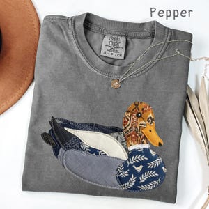 Op de afbeelding: Een witte keramische mok met een zwart handvat en de tekst "But First, Coffee" in een zwarte, vette letter. De mok staat op een houten oppervlak. De mok is ongeveer 10 cm hoog.