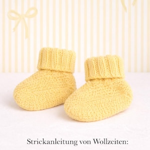 Puede incluir: Un par de patucos de bebé de punto amarillo, con puño acanalado y punto texturizado. El fondo es amarillo claro con un patrón de rayas y detalles de lazo. El texto en la imagen dice "Strickanleitung von Wollzeiten: digitaler Download."