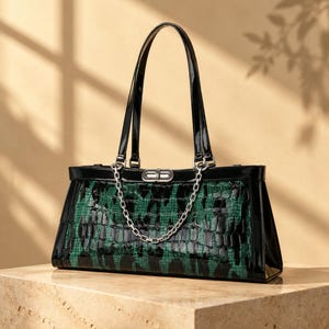 May include: A structured handbag featuring a glossy black patent finish on the top trim and dual handles. The main body displays a textured green and black crocodile-embossed pattern. A silver-toned metal chain drapes across the front.