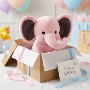 K&ouml;nnte beinhalten: Ein rosa Pl&uuml;schelefant mit dunkelbraunen Innenohren sitzt in einer braunen Geschenkbox, die mit wei&szlig;em Seidenpapier ausgekleidet ist. Die Box ist mit rosa und blauen B&auml;ndern verziert. Eine Karte lautet "Welcome Little One."