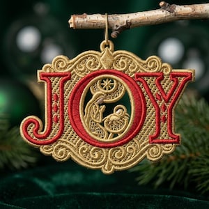 Op de afbeelding: Een goud en rood geborduurd ornament met het woord JOY in een decoratief lettertype. De letter O bevat een gedetailleerde geborduurde scène van een kerststal met een knielende figuur naast een kribbe onder een ster. Het ontwerp heeft krullen.