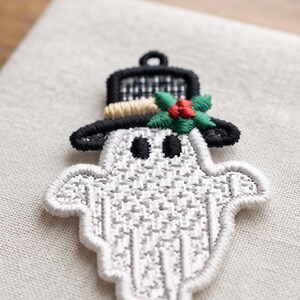 Puede incluir: Un parche bordado que muestra un fantasma blanco con ojos ovalados negros que lleva un sombrero de copa negro. El sombrero est&aacute; decorado con una banda beige y un grupo de hojas de acebo verdes con tres bayas rojas. El fantasma tiene un patr&oacute;n.
