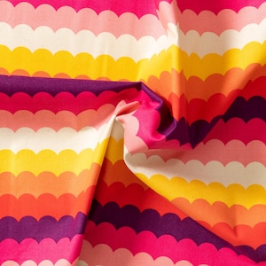 Può includere: Primo piano di un tessuto colorato con un motivo a conchiglia. Il tessuto presenta strisce orizzontali nei toni del rosa, bianco, giallo, arancione e viola. Il tessuto è piegato, mostrando la trama e le variazioni di colore.