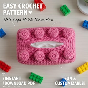 May include: A pink crocheted tissue box cover designed to resemble a Lego brick. The cover features raised, circular details and a rectangular opening for tissue dispensing. The text "EASY CROCHET PATTERN" and "DIY Lego Brick Tissue Box" are visible.